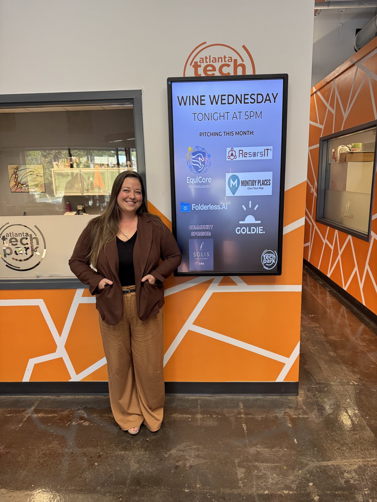 Katelyn Thompson beside Atlanta Tech Park’s pitch-event display featuring Goldie.